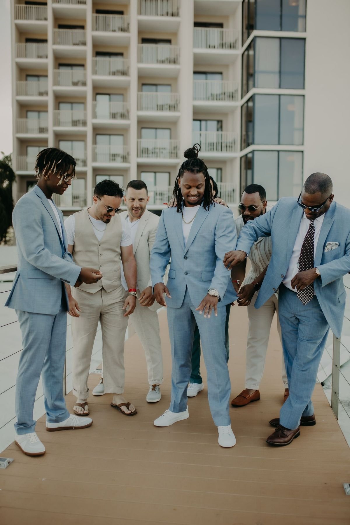 Six friends in light summer suits joking around on a boardwalk